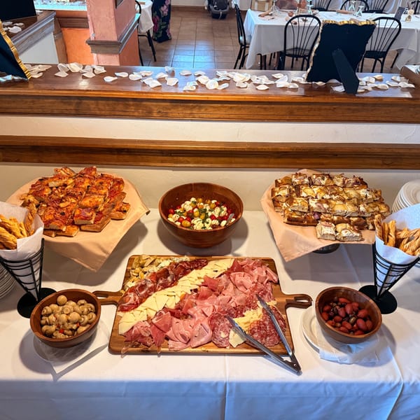 A buffet table laden with Italian appetizers, including focaccia, charcuterie, and caprese salad.