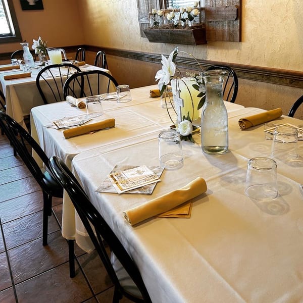 Dining room at Ristorante Maietta with tables set with white tablecloths, yellow napkins, and water pitchers.