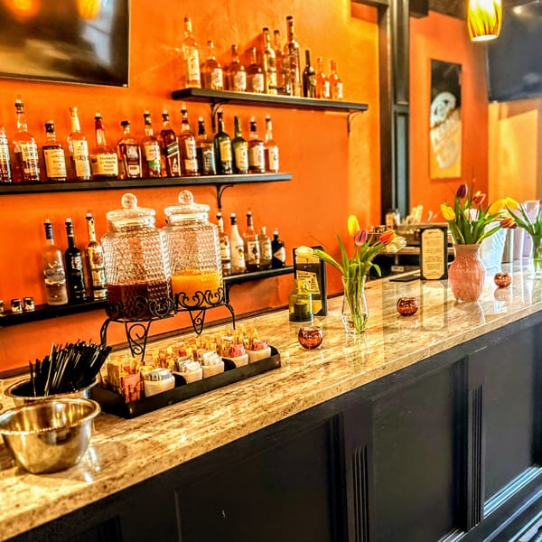 A bar at Ristorante Maietta with liquor bottles, drink dispensers, and fresh tulips.