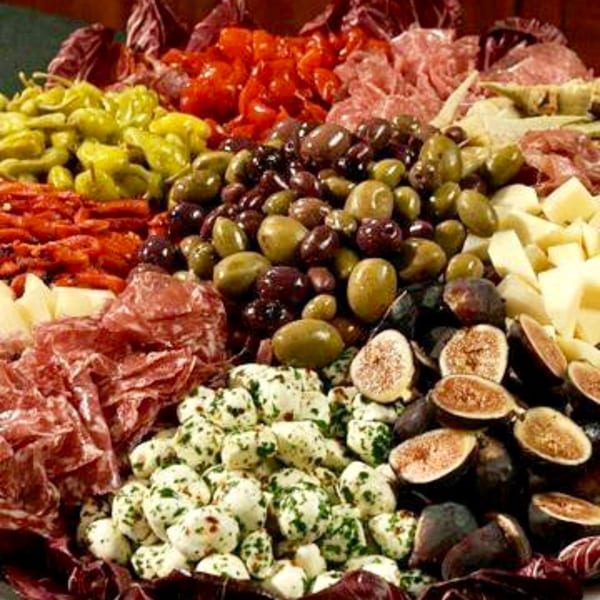 A vibrant Italian antipasto platter with meats, cheeses, olives, peppers, sun-dried tomatoes, and figs.