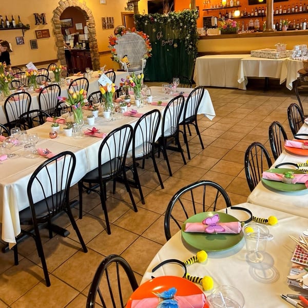 Restaurant dining room set for a baby shower with decorated tables, chairs, and a "Oh Baby" backdrop.